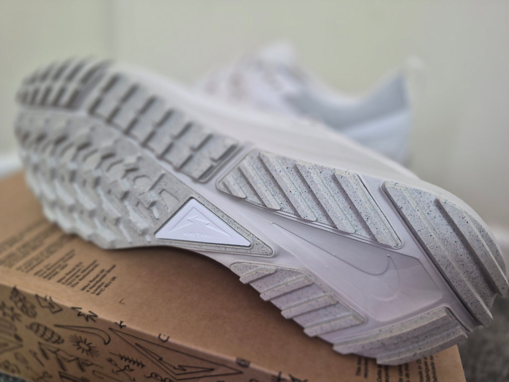 A close-up of a white Nike sneaker showing its textured gray and white outsole.