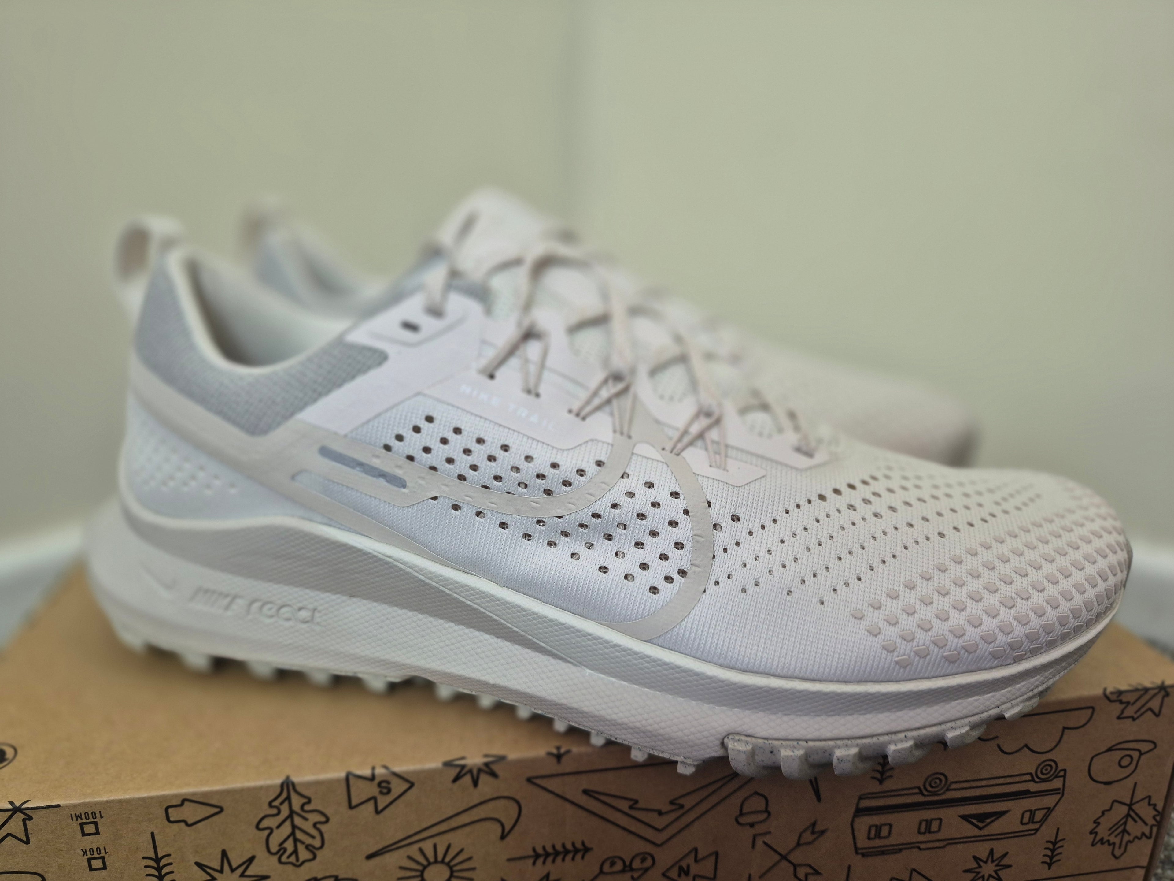 A pair of Nike running shoes in white and light gray, side view.
