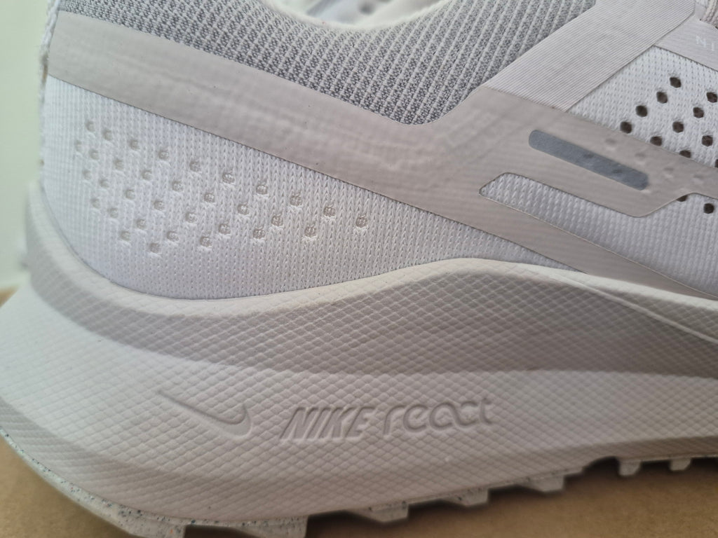 Close-up of a white Nike running shoe showing the side profile with the Nike logo and 'NIKE FEEL' text on the midsole.